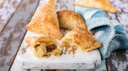 Apfeltaschen mit Blätterteig auf einem Mamorbrett.