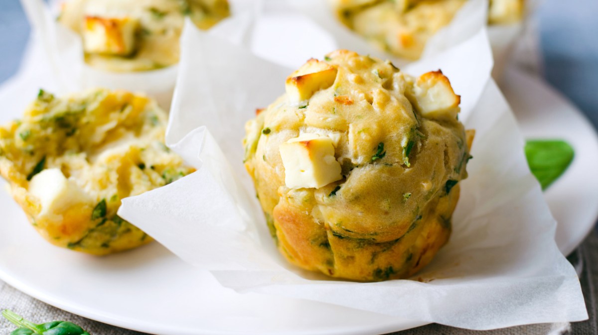 Herzhafte Muffins mit Feta und Rucola auf weißem Teller.