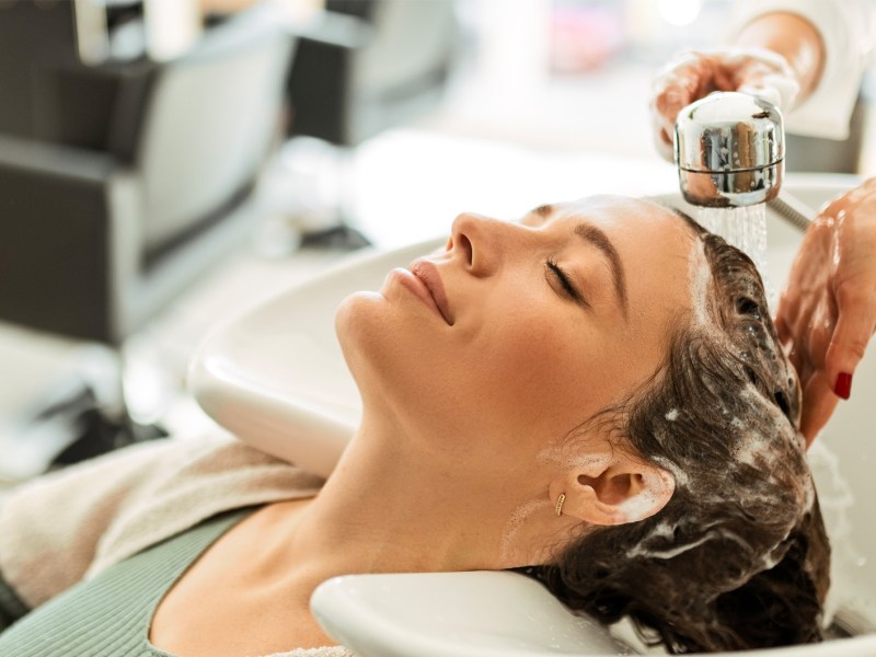Frau, die im Haarsalon die Haare gewaschen bekommt.