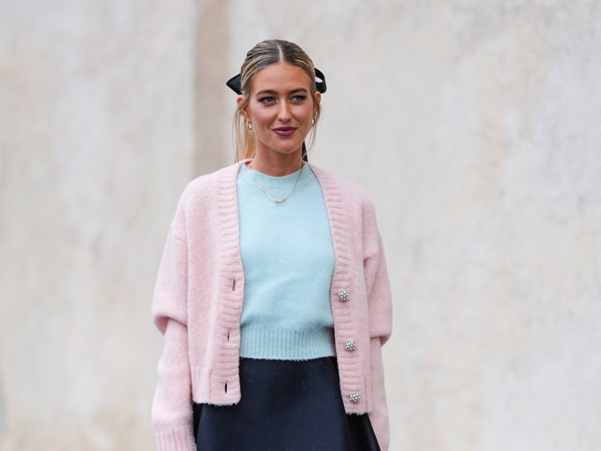 Emili Sindlev in einem rosa-verspielten Cardigan mit Schleife im Haar