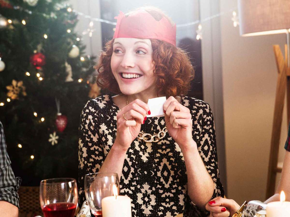 Frau hat eine Krone auf und spielt mit ihren Freund*innen ein Partyspiel zu Silvester.