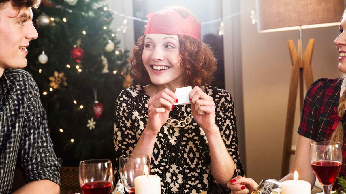 Frau hat eine Krone auf und spielt mit ihren Freund*innen ein Partyspiel zu Silvester.
