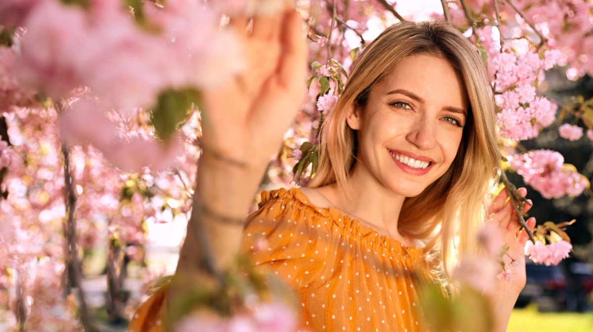 Frau in gelber Bluse zwischen Kirschblüten