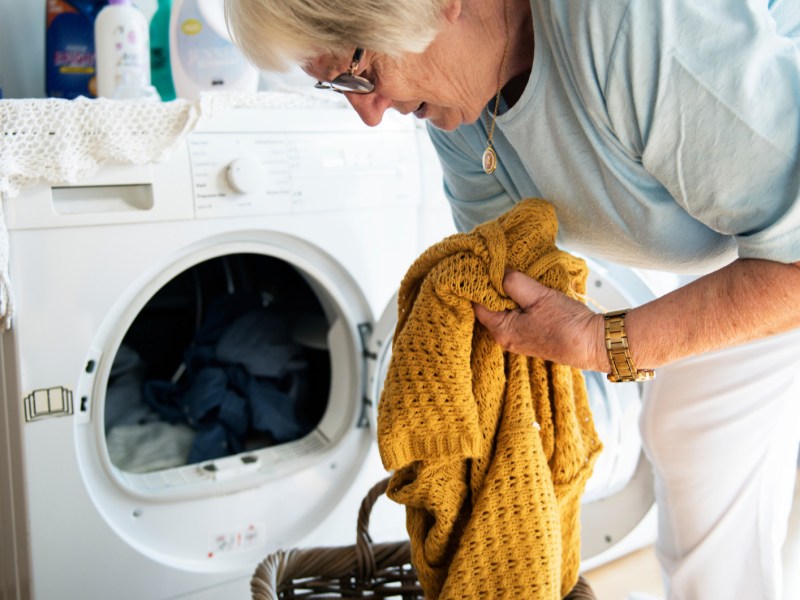 Ältere Frau räumt Waschmaschine aus.