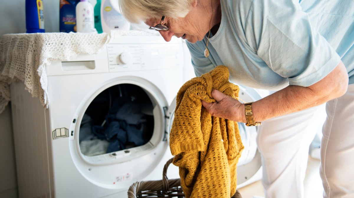 Ältere Frau räumt Waschmaschine aus.