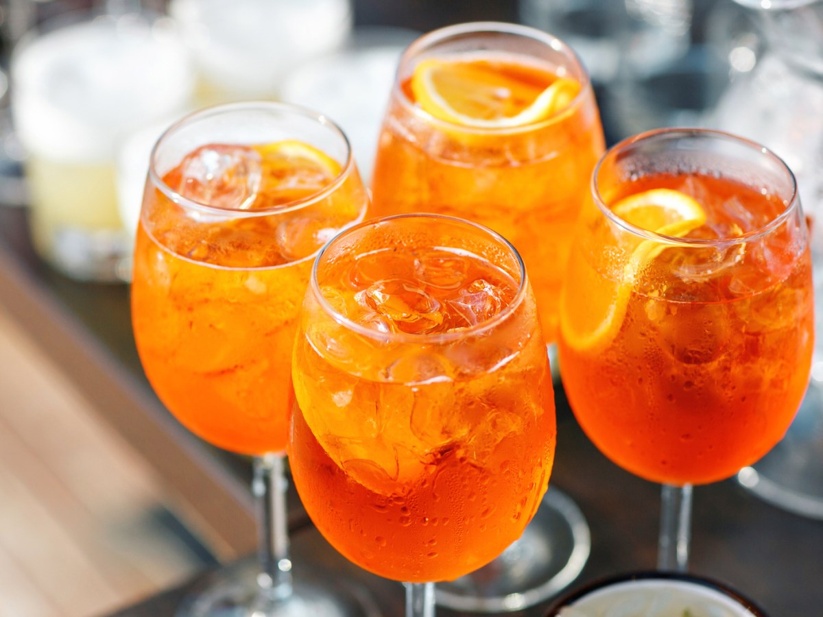 Vier Gl&auml;ser mit Aperol Spritz auf einem Tisch.
