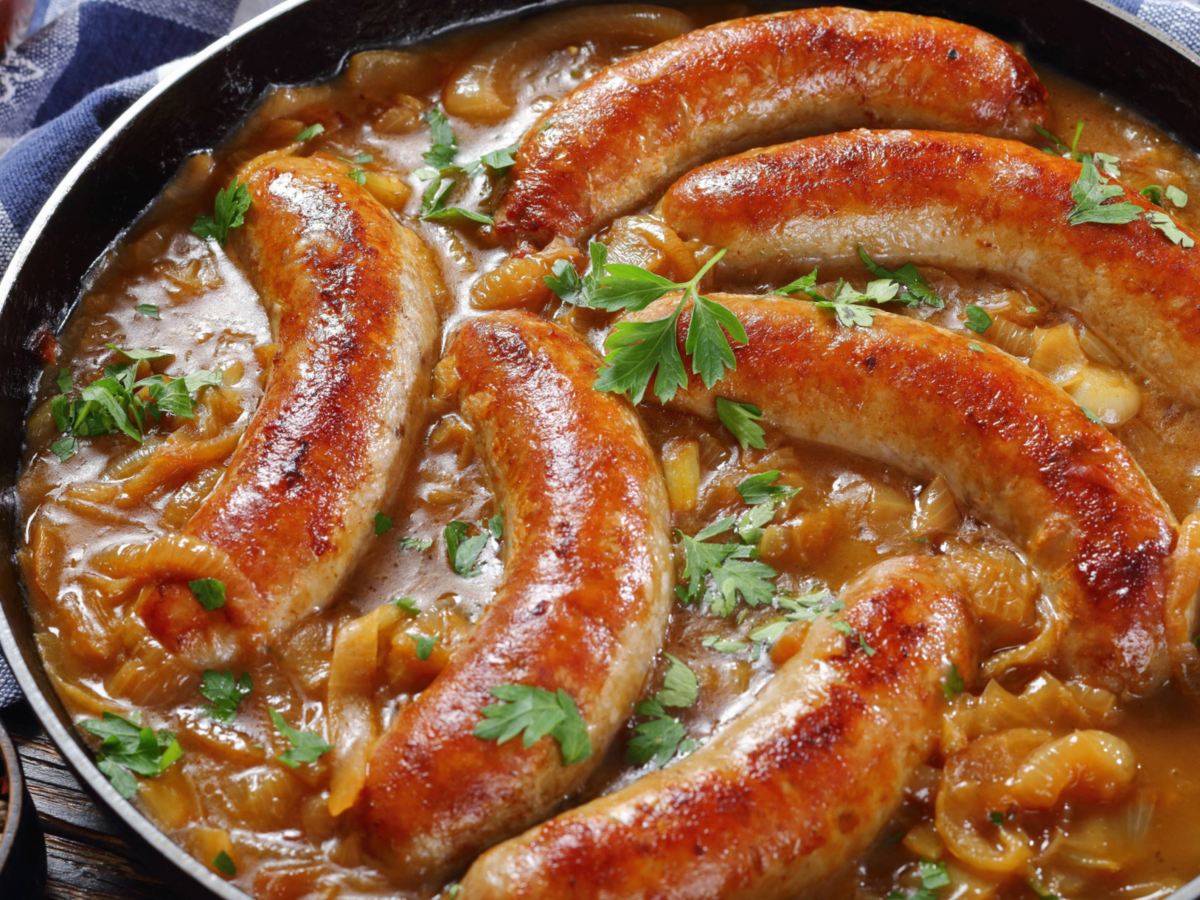 Bratw&uuml;rste in Pfanne mit dunkler So&szlig;e.