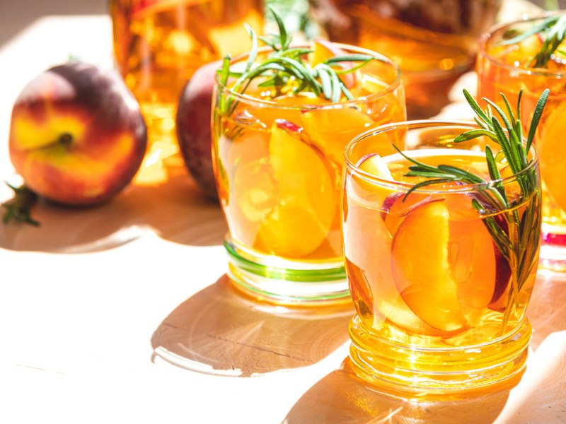 Cocktail mit Pfirsichscheiben bei Abendsonne.