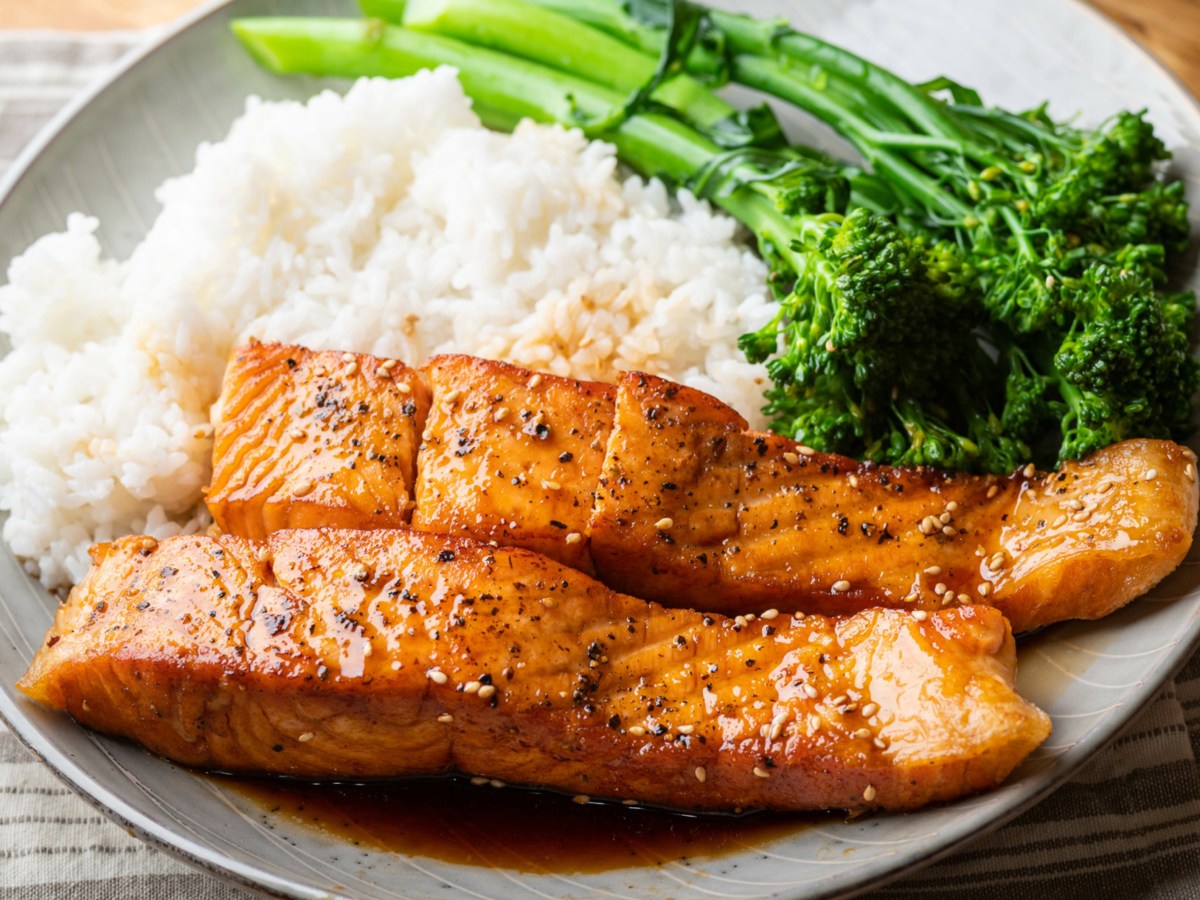 Teriyaki-Lachs mit wei&szlig;em Reis und Brokkolini auf beigem Teller.