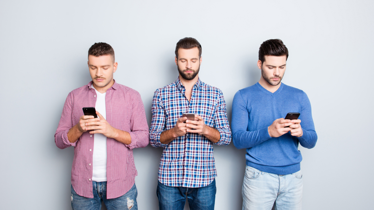 Drei Männer mit Handy in der Hand, die auf das Display schauen und tippen.
