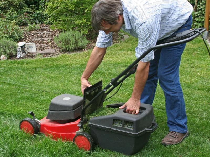 Mann leert Behälter von Rasenmäher.