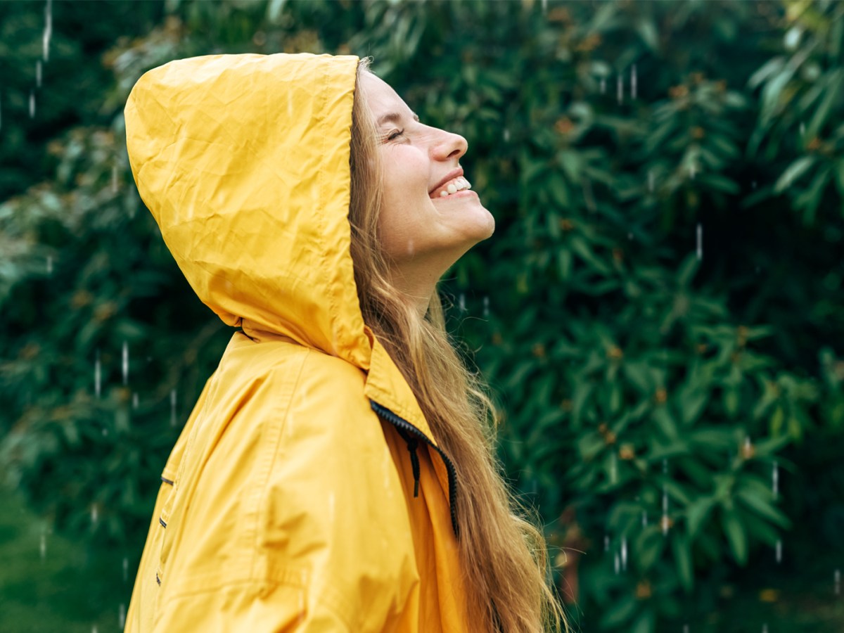 Frau, die im Regen tanzt und nach oben schaut