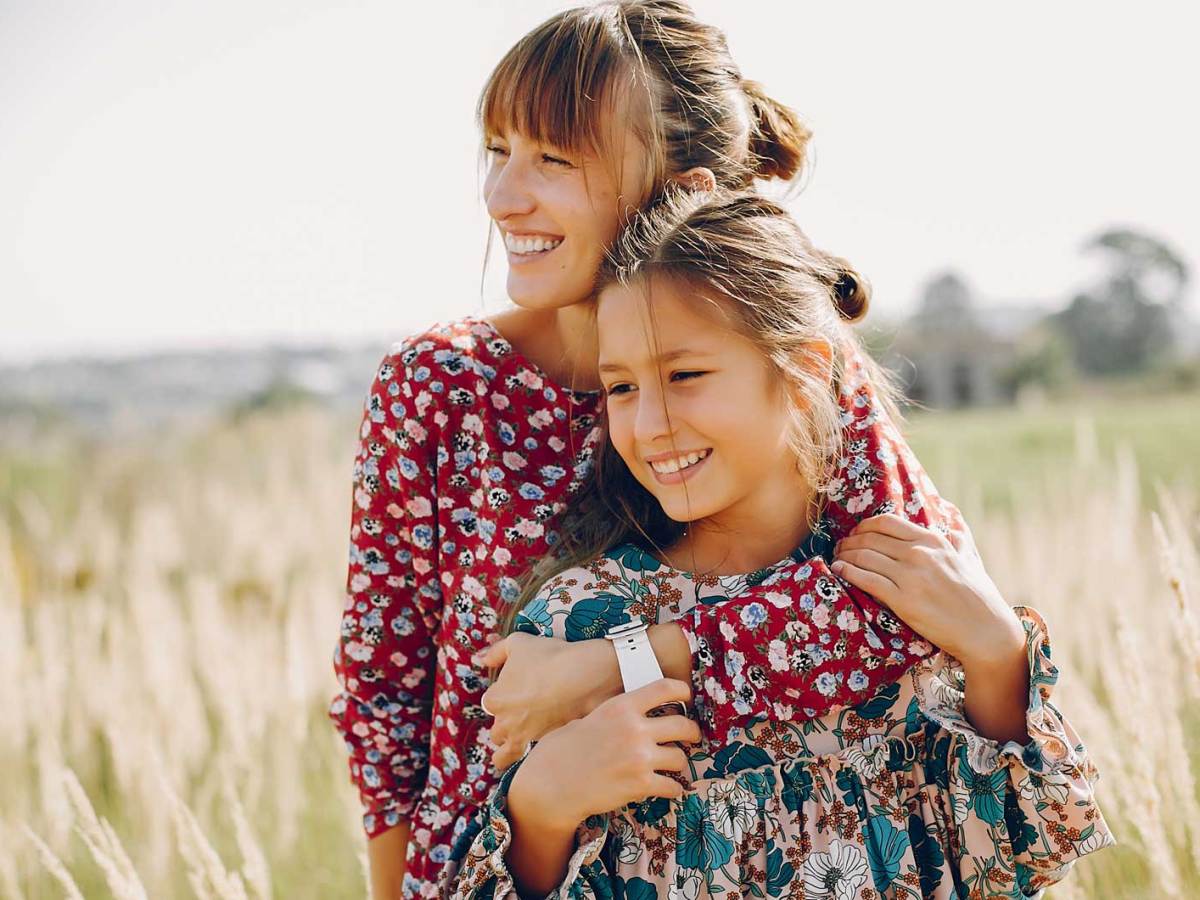 Mutter und Tochter stehen in einem blühenden Feld.