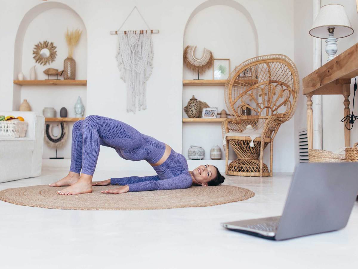 Fitte Frau trainiert zu Hause und macht &Uuml;bung Ges&auml;&szlig; Br&uuml;cke