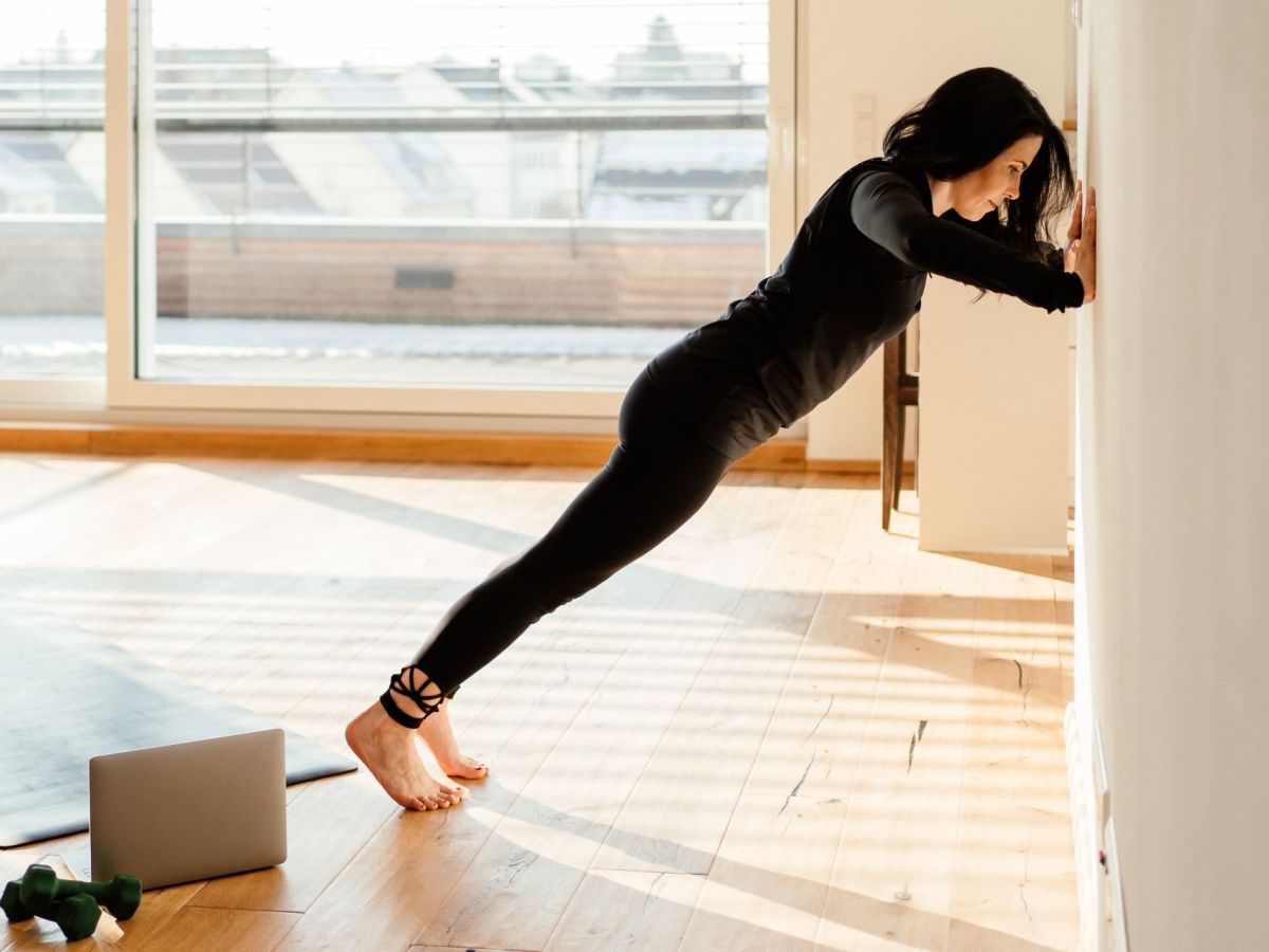 Wand Pilates &Uuml;bungen: Frau in schwarzer Trainingskleidung macht Wall Push up