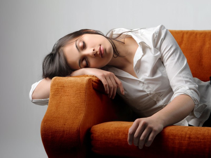 Frau sitzt m&uuml;de auf dem Sofa