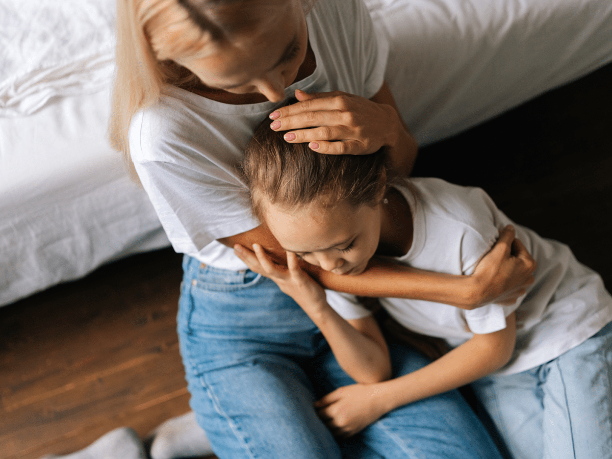 Frau mit Kind auf dem Scho&szlig;, das getr&ouml;stet wird.