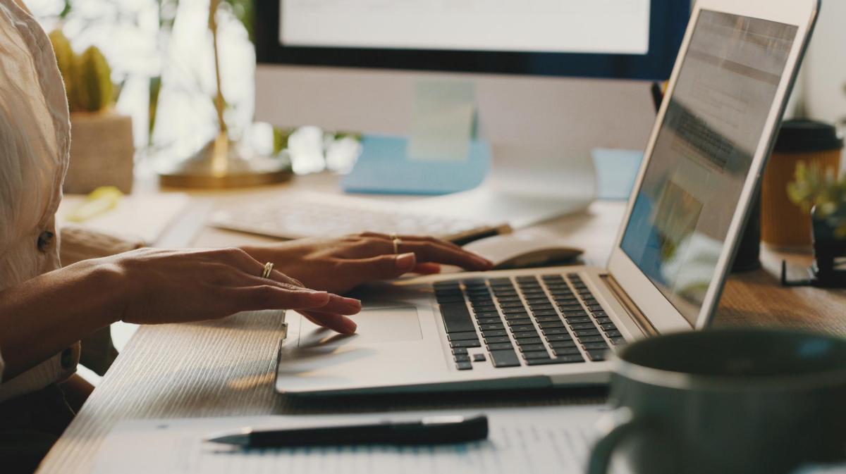 Frau tippt auf einem Laptop.