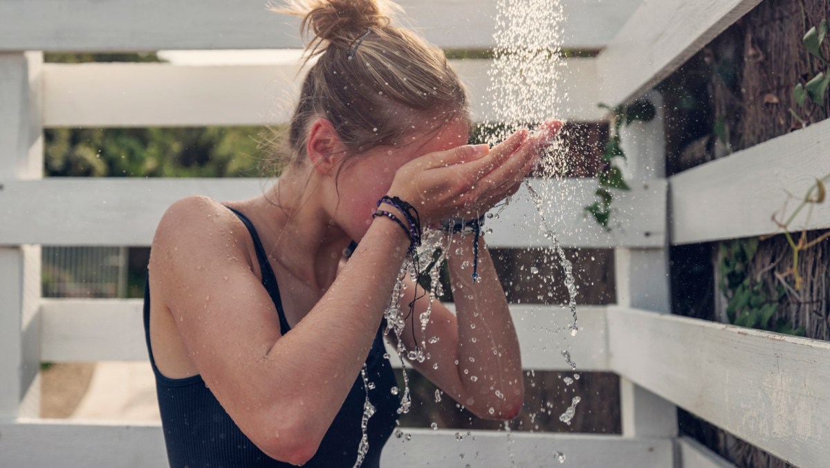 Frau duscht sich im Freien und erfrischt sich bei Hitze.