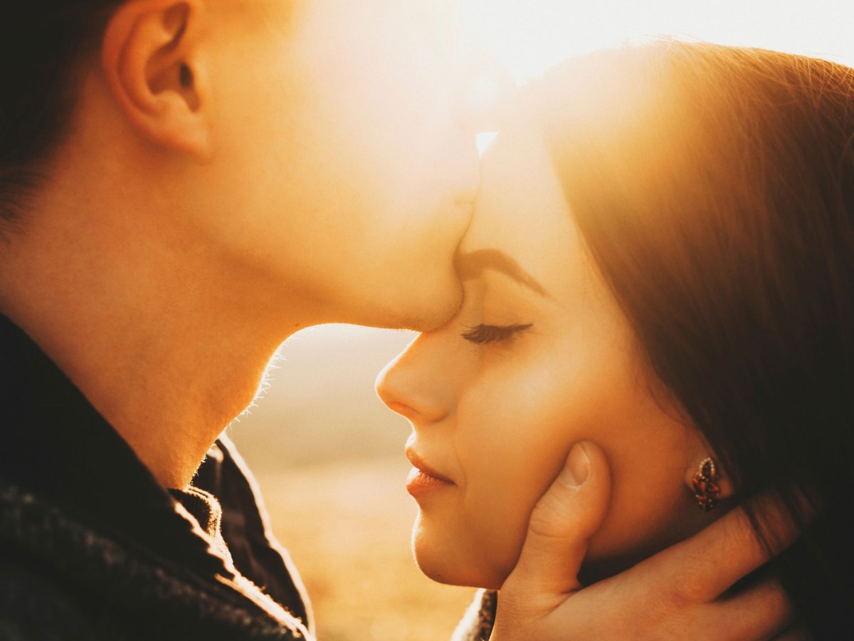 Mann k&uuml;sst Frau auf die Stirn bei Sonnenschein
