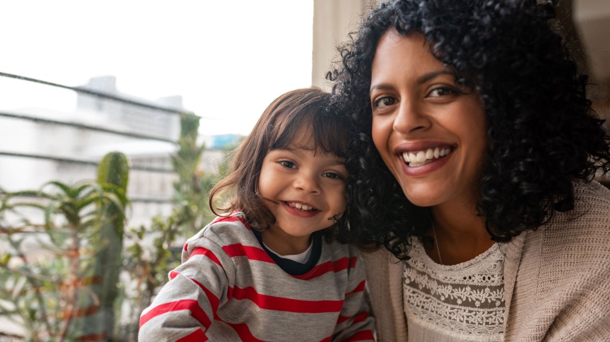 Lachende Mutter mit ihrer Tochter auf dem Balkon ihres Zuhauses.