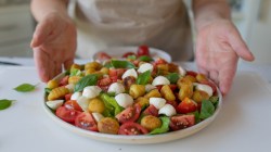 Salat mit Gnocchi, Tomaten, Mozzarella und Basilikum in einer gro&szlig;en Schale.
