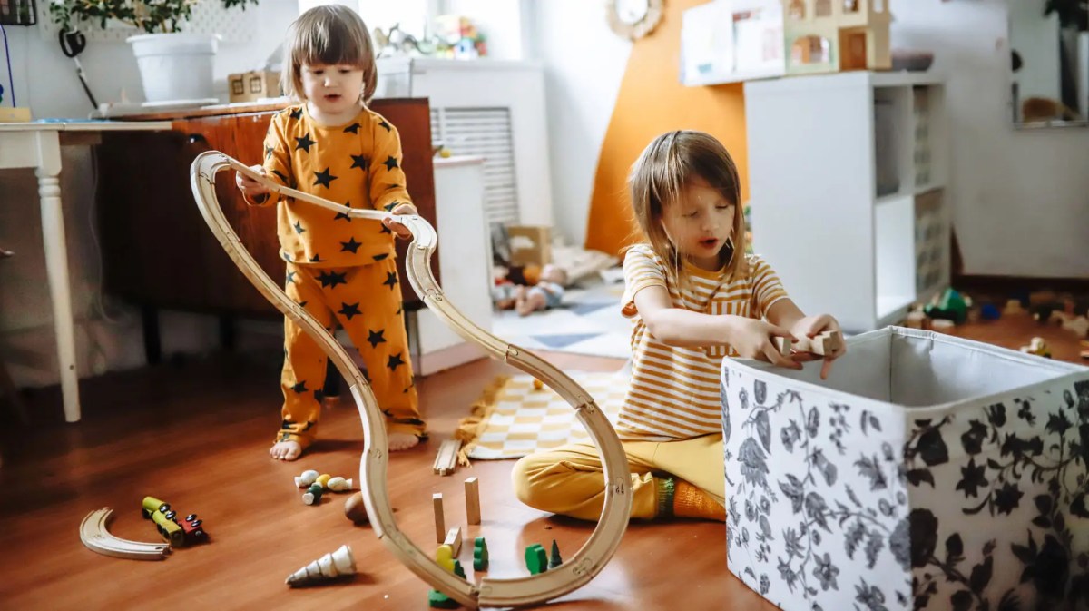 Zwei Kinder in ihrem Kinderzimmer beim Aufräumen der Spielsachen.
