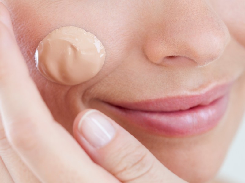 Frau mit einem Tropfen Make-up auf der Wange.