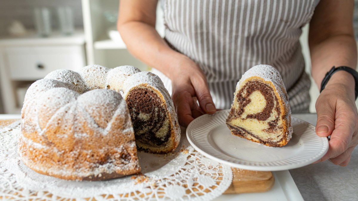 Person hat Stück Gugelhupf auf Kuchenteller.