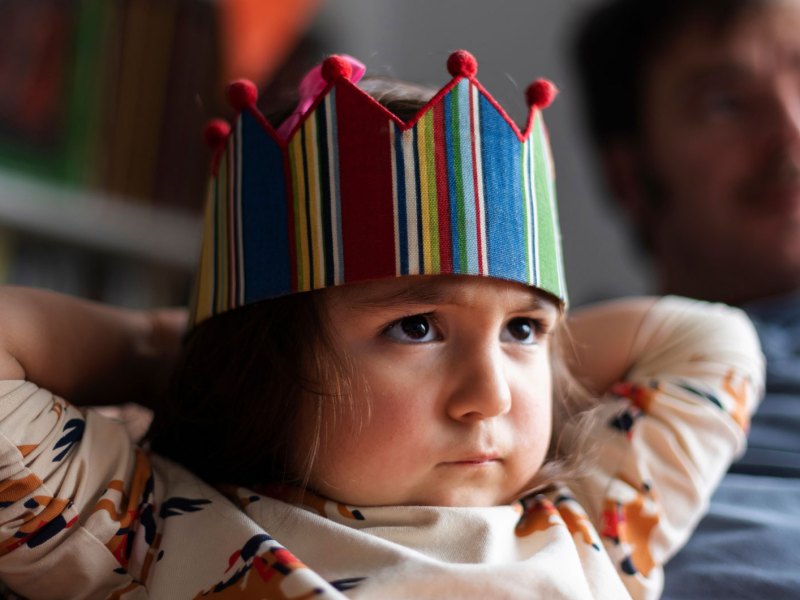 Porträt eines kleinen, wütenden Mädchens mit einer Geburtstagskrone auf dem Kopf.