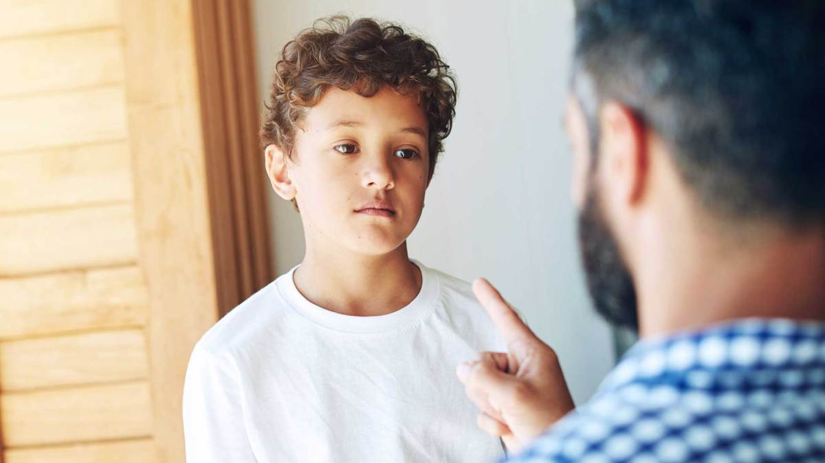 Vater schimpft mit seinem Sohn im Teenageralter. Der schaut genervt.