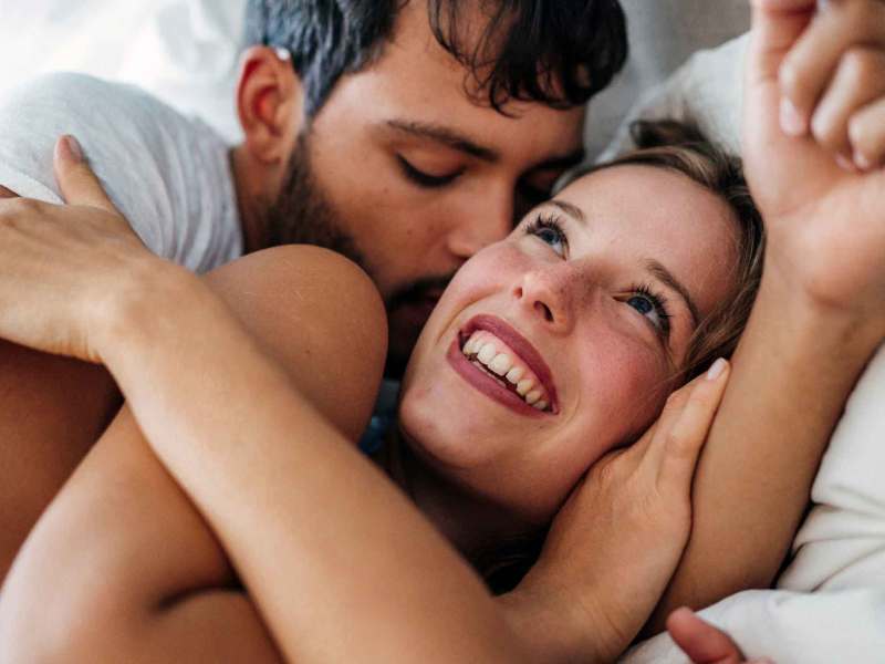 Mann küsst Frau auf Schläfe.