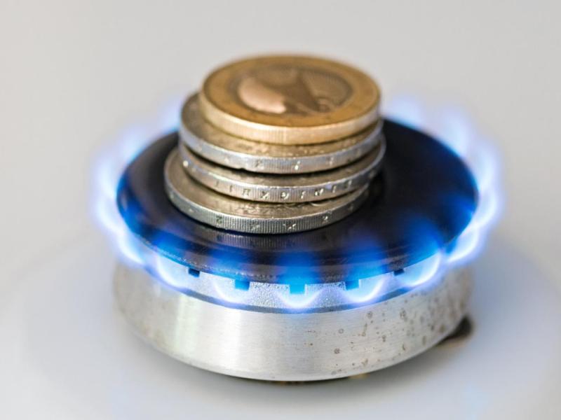 Geldmünzen liegen auf einer Gasflamme.