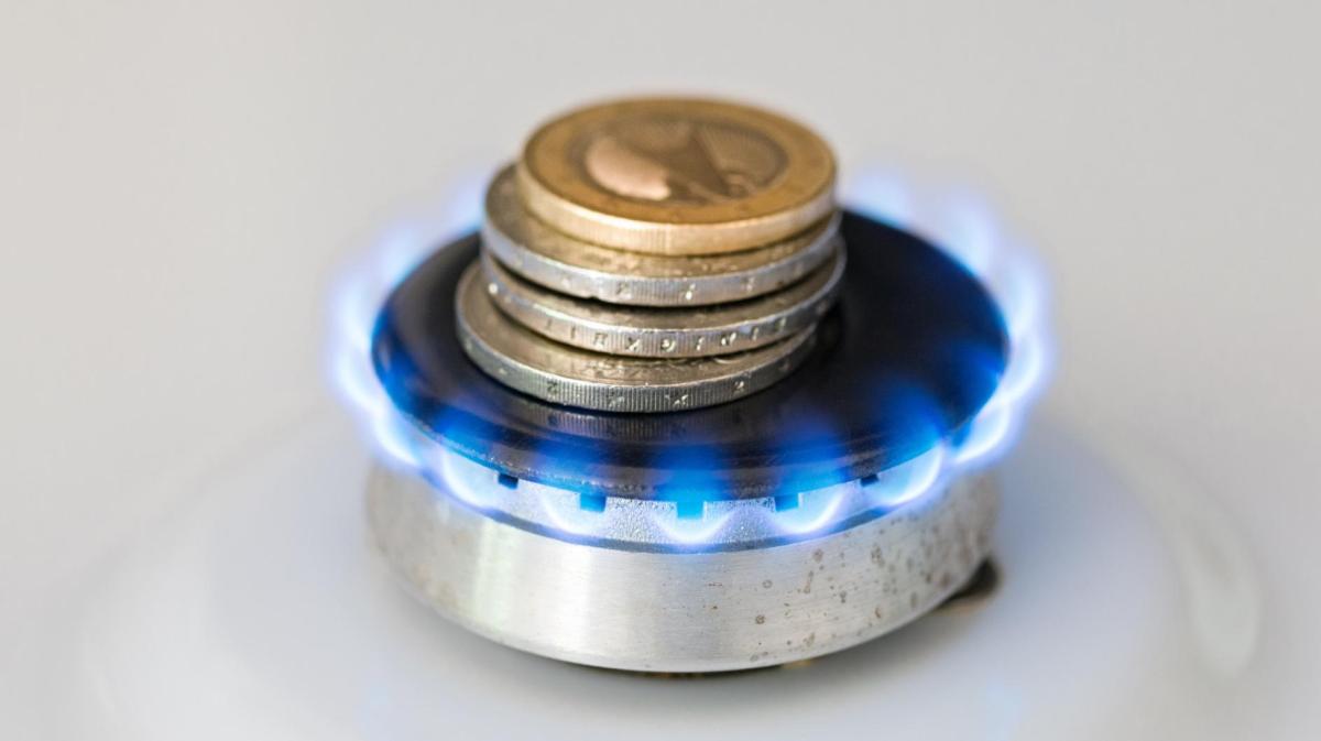 Geldmünzen liegen auf einer Gasflamme.