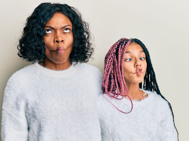 Mutter und Tochter im Partnerlook posieren witzig für die Kamera. Beide machen einen Fischmund.