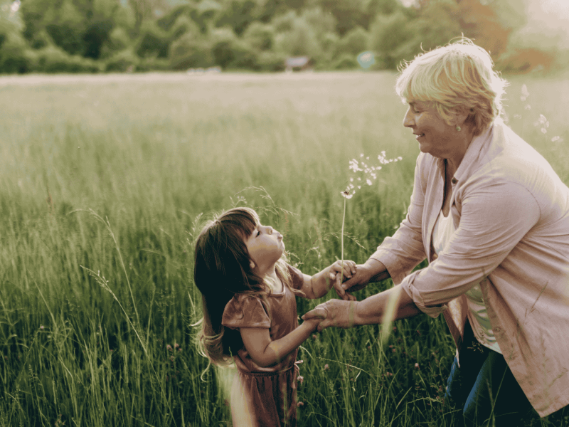 Großmutter und Enkelin auf einer Blumenwiese lachend