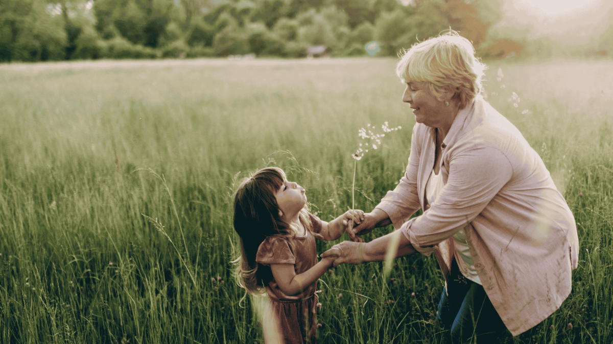 Großmutter und Enkelin auf einer Blumenwiese lachend