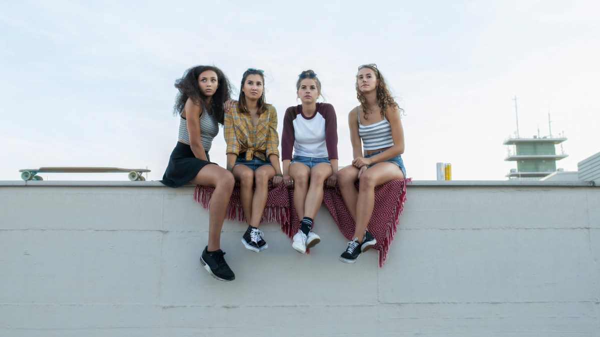 Gruppe Teenie-Mädchen sitzt auf einer Mauer und schaut in die Ferne.
