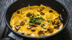 Rührei mit Pilzen und Frühlingszwiebeln in der Pfanne braten