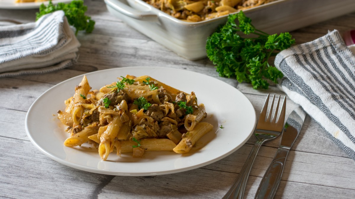 Spitzkohlpfanne mit Hackfleisch und Nudeln auf einem weißen Teller.