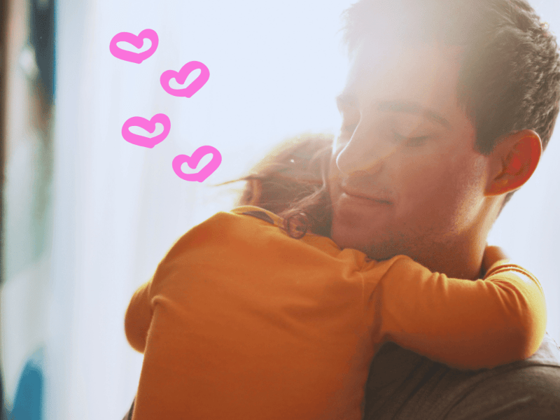 Papa hat Kind auf dem Arm und kuschelt, daneben Herzen