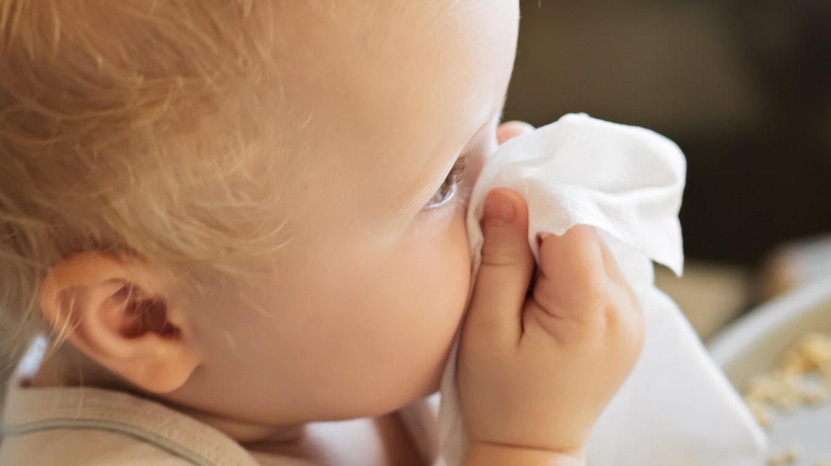 Baby hält ein Taschentuch vor der Nase