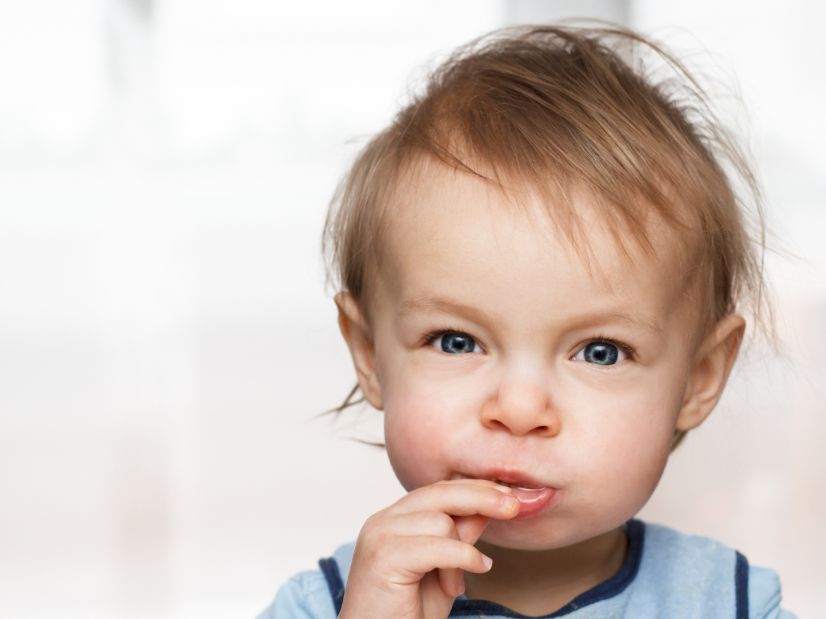 Kleinkind schaut in die Kamera und isst etwas