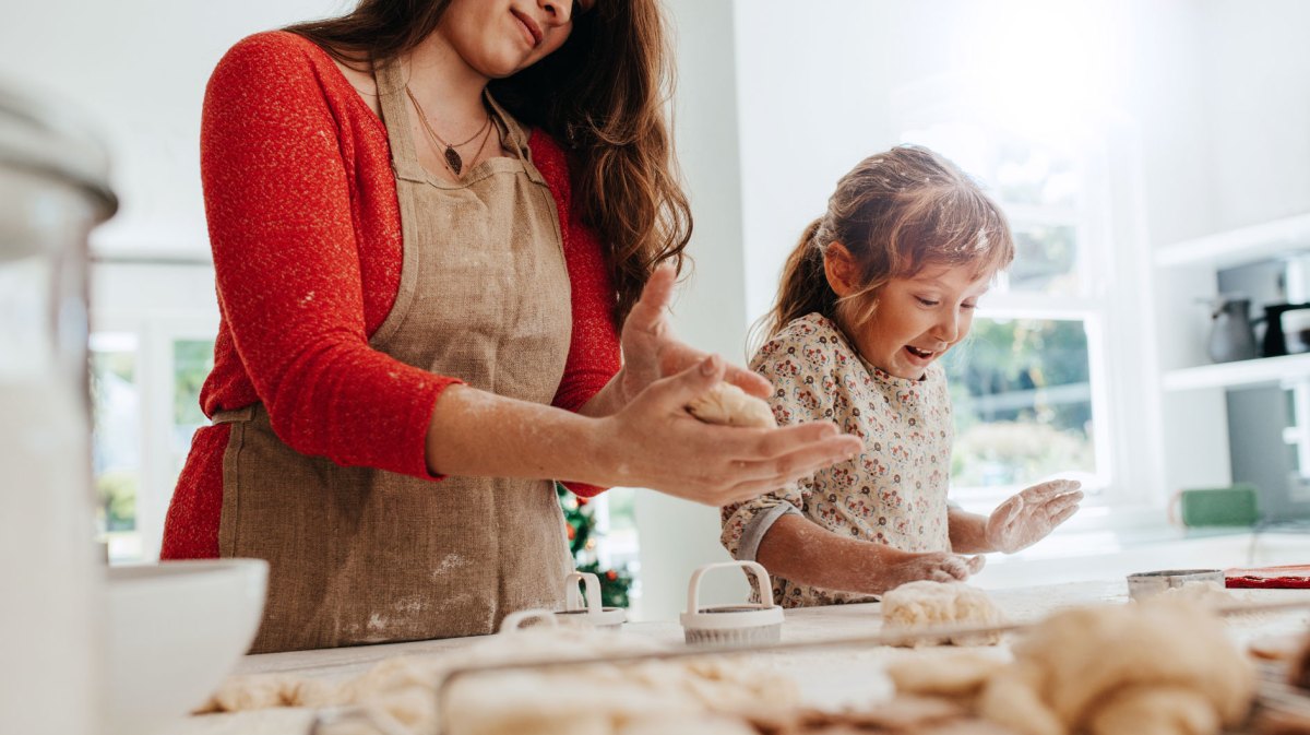 Mtter und Tochter haben sichtlich Spaß beim Backen von Weihnachtsplätzchen.