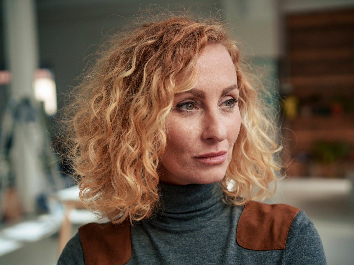 Frau mit lockigem blonden Haar schaut nachdenklich als Symbolbild f&uuml;r Sternzeichen Fische