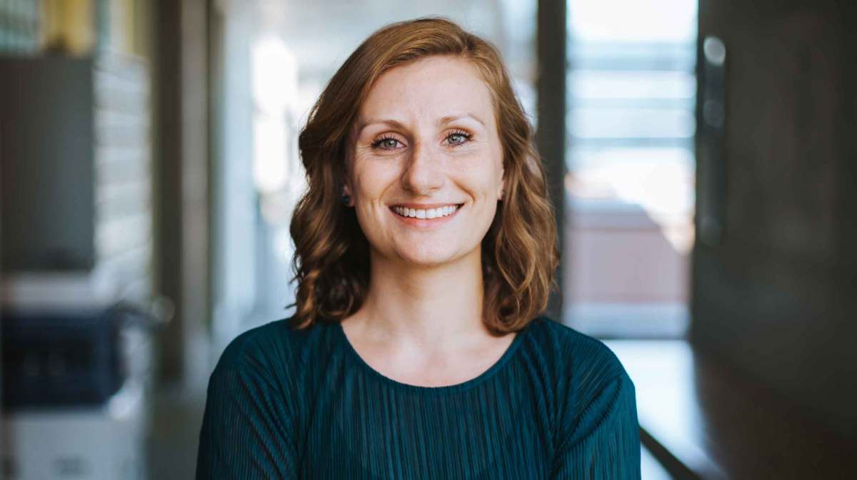 Selbstbewusste junge Frau im Job steht da mit verschränkten Armen.