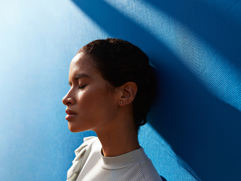 Frau vor einer blauen Wand blickt traurig