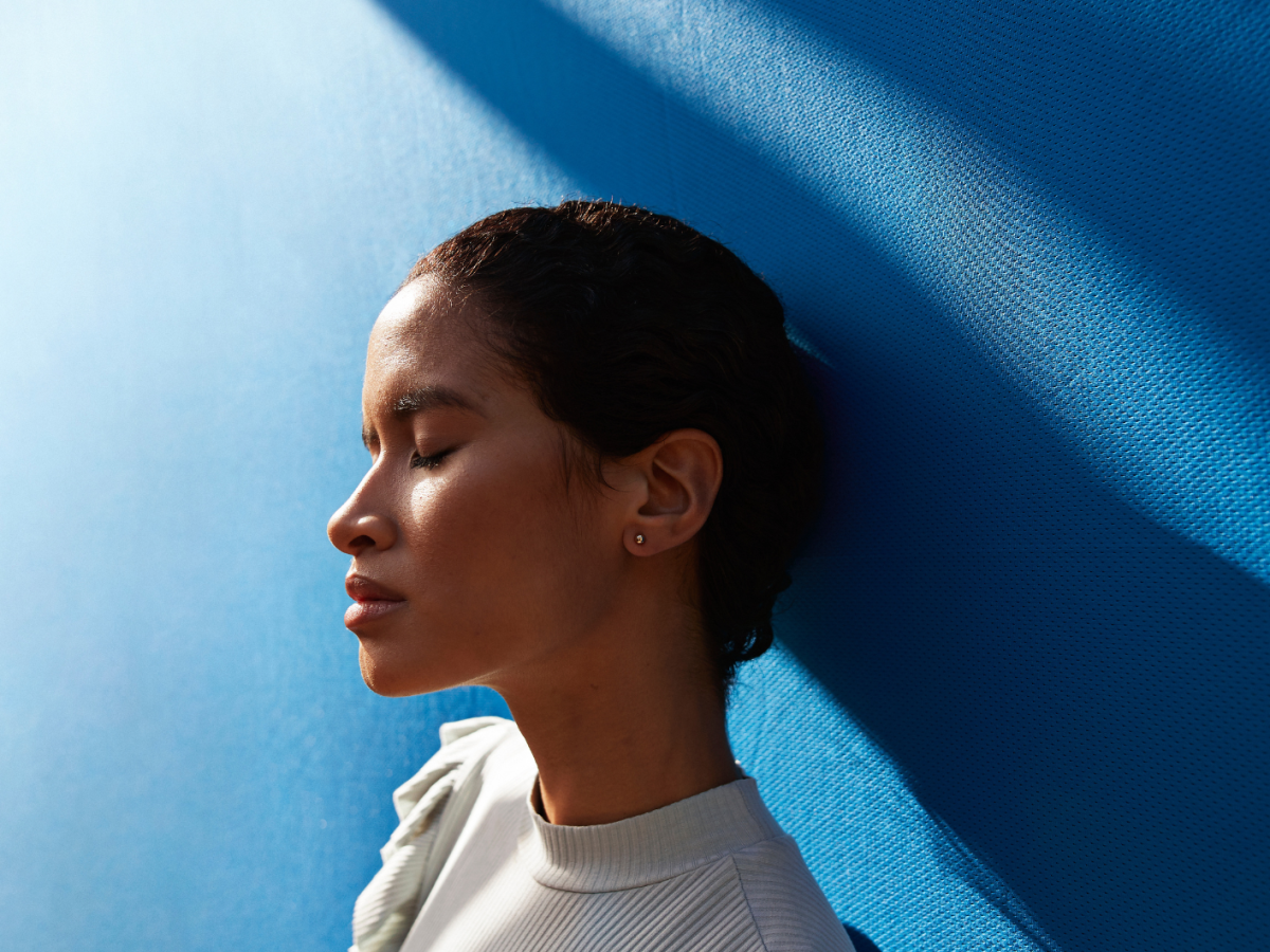 Frau vor einer blauen Wand blickt traurig