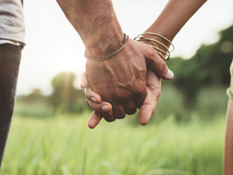 Zwei Hände, die sich halten vor einer Wiese