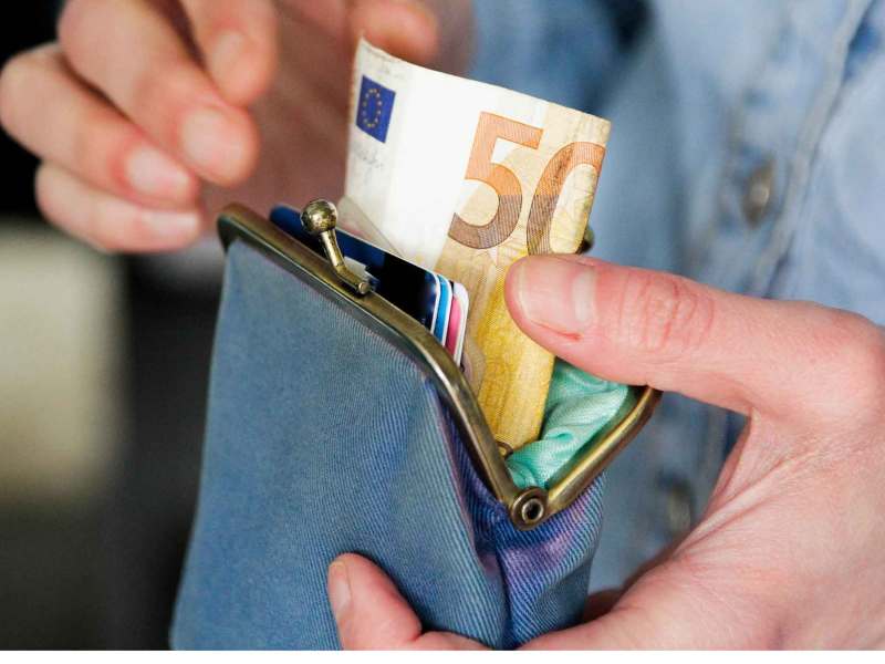 Person nimmt Geld aus dem Portmonnaie.